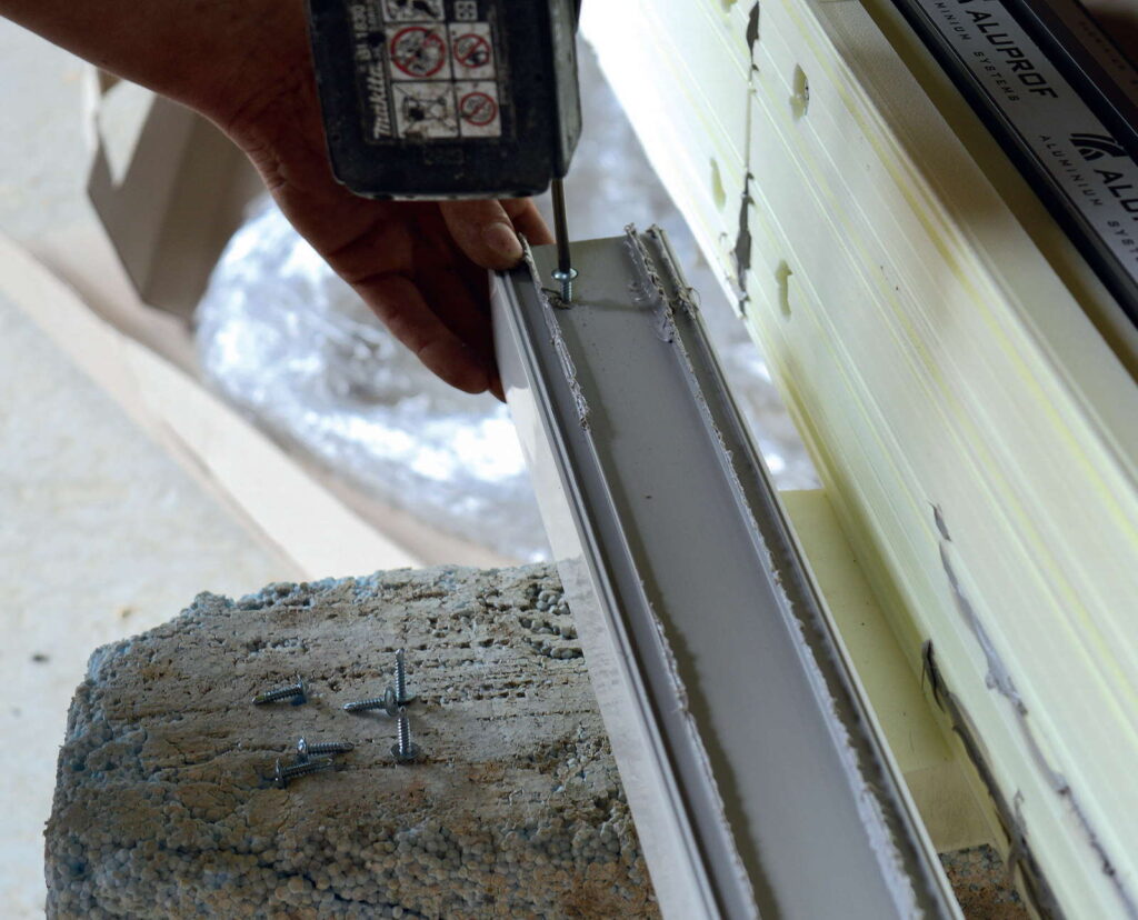 Poszerzenie z PVC zamocowane zostały do spodu podwaliny z XPS – najpierw na warstwę kleju...